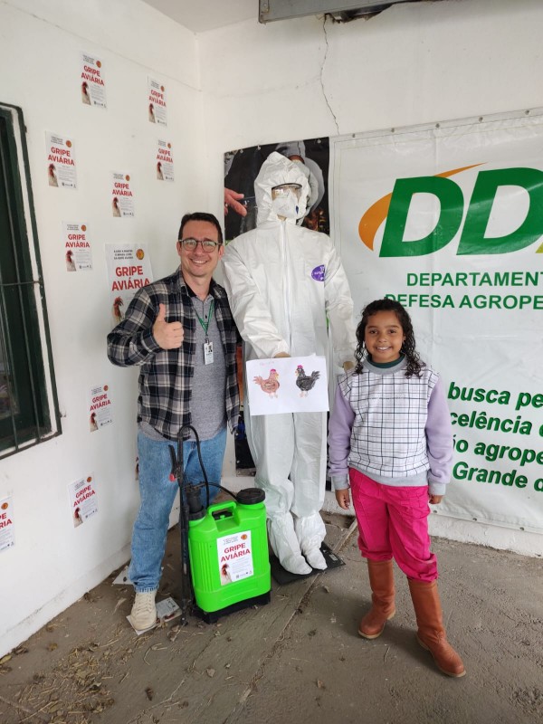 O coordenador de Educação Sanitária da Seapi, Felipe Campos, com a menina Alícia, que aprendeu mais sobre gripe aviária