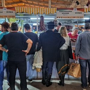 Várias pessoas de costas diante de duas barracas de produtores rurais no Pavilhão da Agricultura Familiar na Expointer.