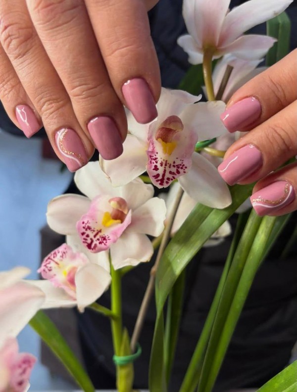 Na imagem, duas mãos de unhas feitas com flores combinando